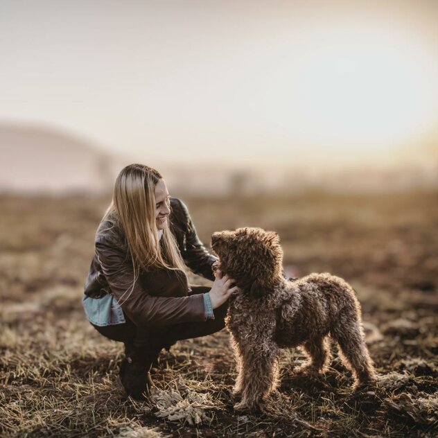 blonde Frau kniet neben Hund beide scheuen sich vertrauensvoll an