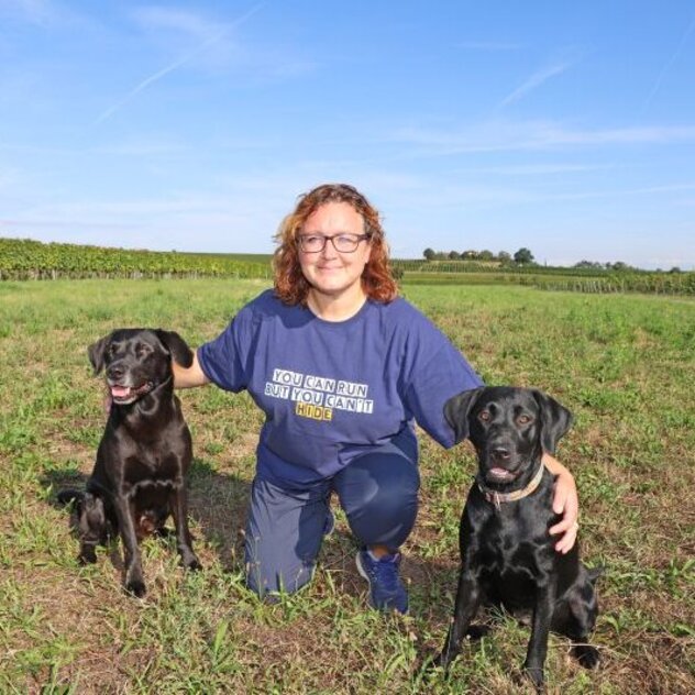 Hundetrainerin Sandra Sauer mit ihren Hunden auf einer Wiese