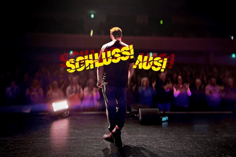 Martin auf der Bühne von hinten und Tourtitel SCHLUSS! AUS!