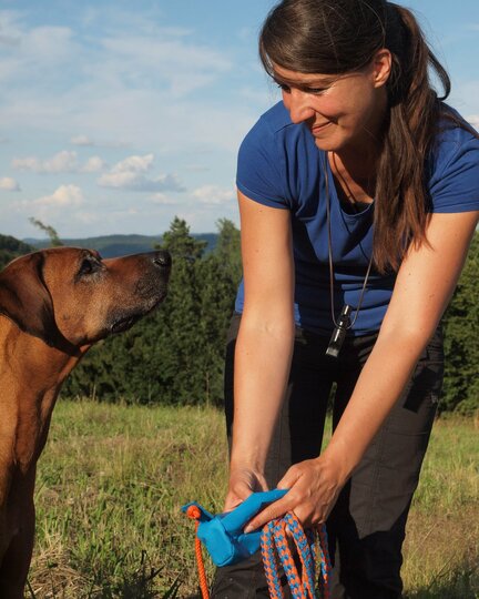 Christiane auf der Wiese mit Ihrem Rhodesian Ridgeback Rüden Tangens und dem blauen Futterbeutel