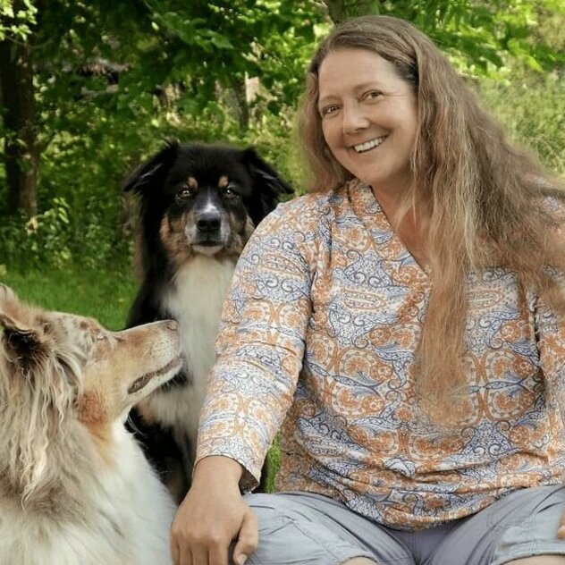 Conny im grünen Garten mit ihren Hündinnen Pia und Sari