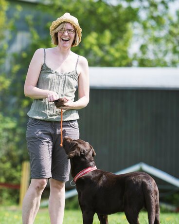 Halter öffnet den Futterbeutel. Hund wartet erwartungsvoll.