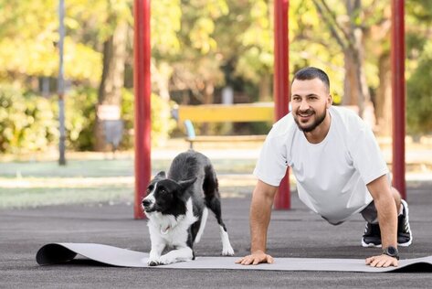 Mensch und Hund trainieren gemeinsam Fitnessübungen im Freien