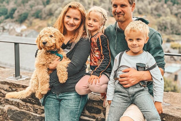Familie mit 2 Kindern und Hund auf dem Arm