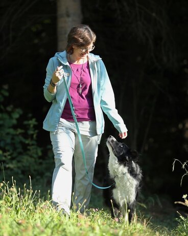 Der Hund läuft leinenführig neben dem Menschen. Sie haben Blickkontakt.
